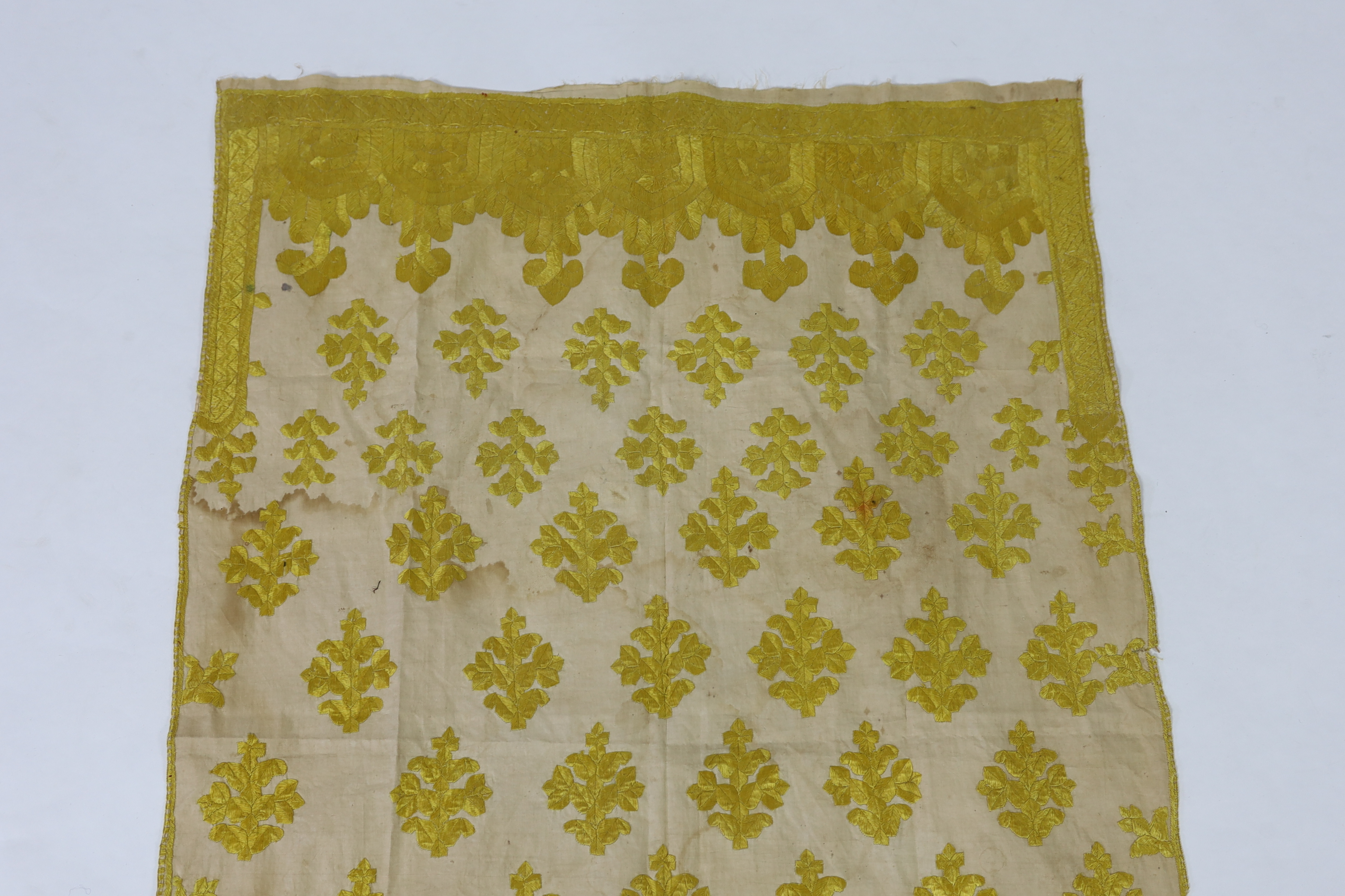 An early 20th century North Indian cotton yellow silk hand embroidered panel, with wide embroidered borders and all over stylistic spot motifs, 122 cm long x 80cm wide